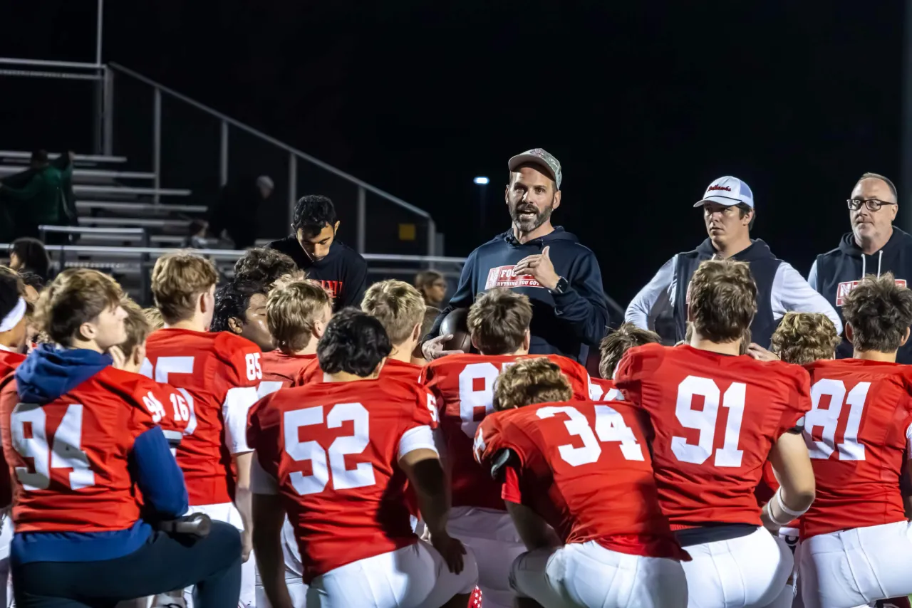 A coach talking to his football team at night, photographed by Connor